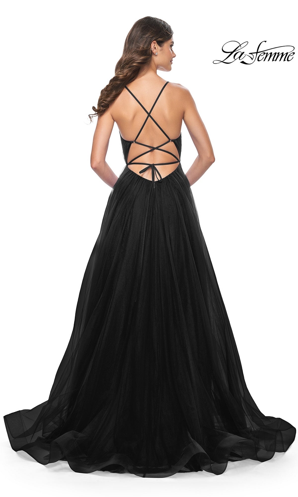 Woman in a floor-length black La Femme Sheer-Waist Long Prom Ball Gown 31457 with crisscross open back and tulle skirt, standing with her back to the camera.